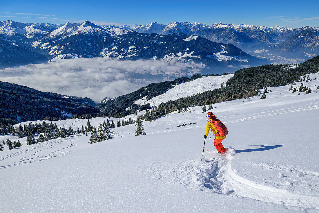 Frau bei Tiefschneeabfahrt vom Wiedersberger Horn, Tuxer Alpen und Karwendel im Hintergrund, Kitzbüheler Alpen, Tirol, Österreich