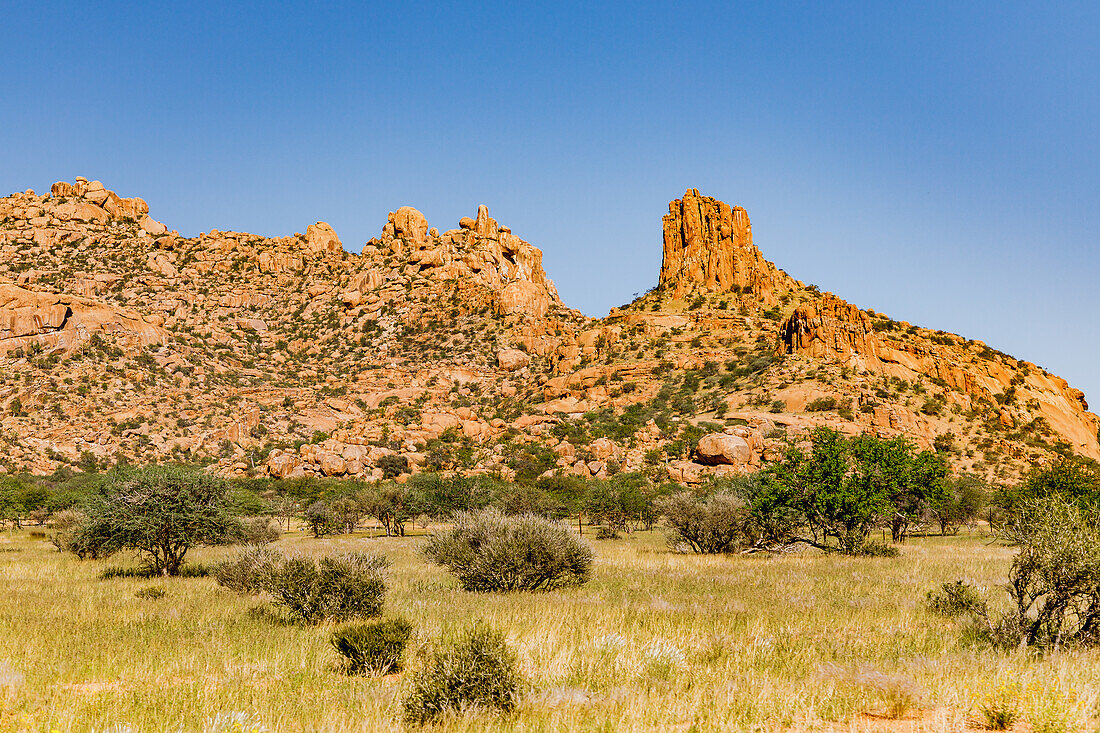 Bushland with shrubs and prominent granite boulders in the Erongo Mountains with blue sky in Namibia, Africa