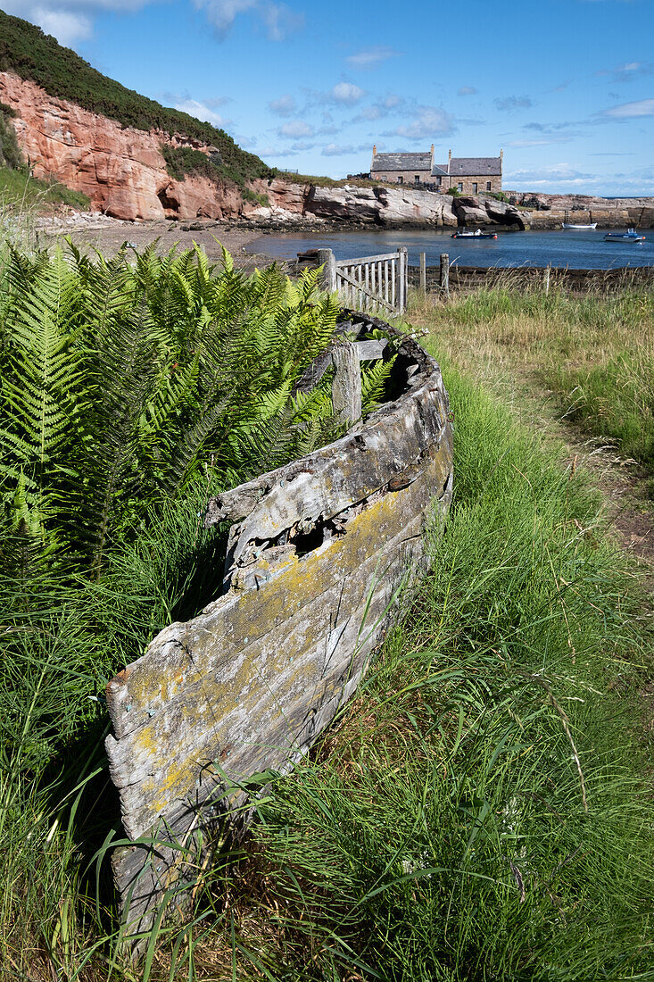 Blick auf einen verlassenen Hafen mit altem Holzboot im Vordergrund, East Lothian, Schottland, Vereinigtes Königreich