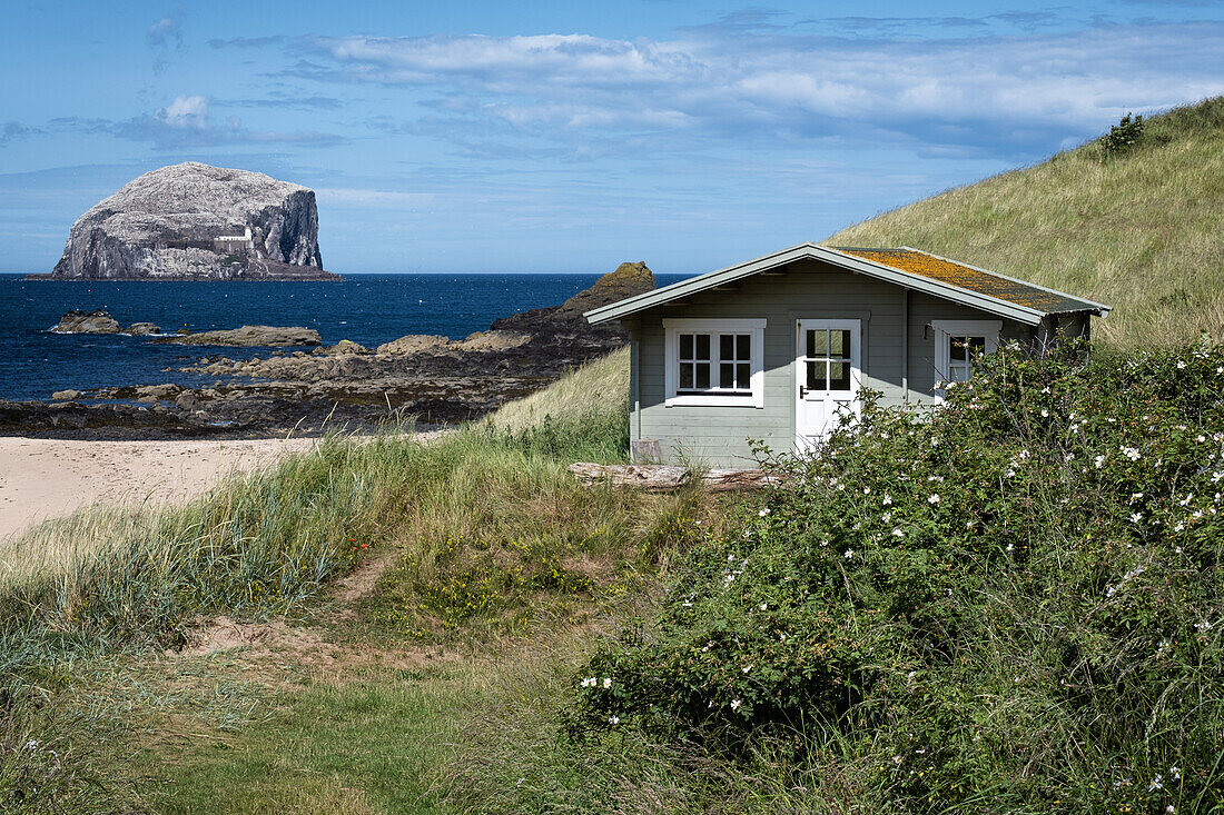 View of Bass Rock with beach house in foreground, East Lothian Coast, Scotland, UK