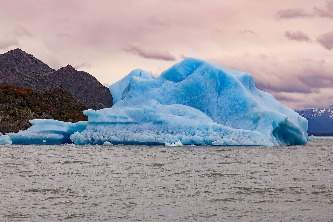 A prominent iceberg in Lago Gray against a cloudy sky in the evening light, Chile, Patagonia