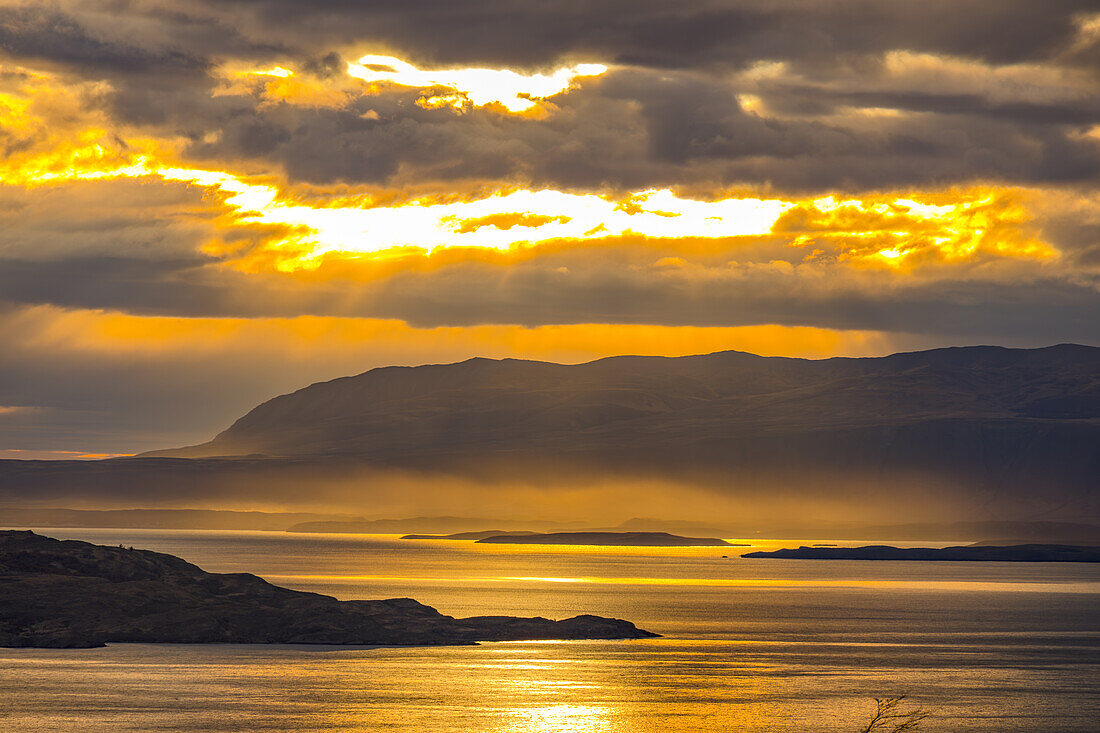 Sunset with dramatic clouds and backlit fog over Lago el Toro, Chile, Patagonia, South America