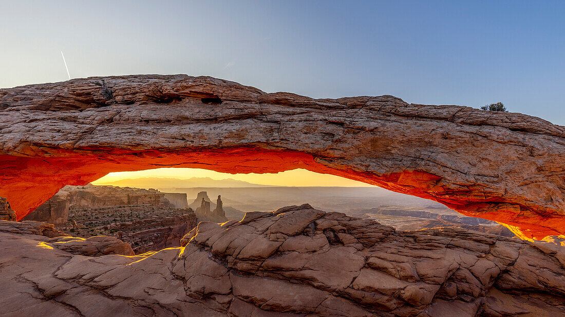 Der Mesa Arch im Canyonlands National Park wird während Sonnenaufgang von der Sonne von unten orange angeleuchtet, Utah, USA