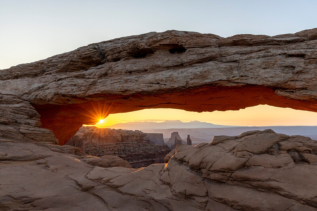 Sonne scheint durch den Felsbogen Mesa Arch zum Sonnenaufgang, Canyonlands National Park, Utah, USA