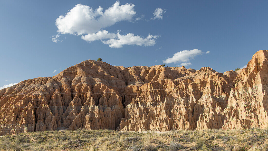 Red yellow divided rugged mountain wall against a blue sky in Cathedral Gorge State Park.