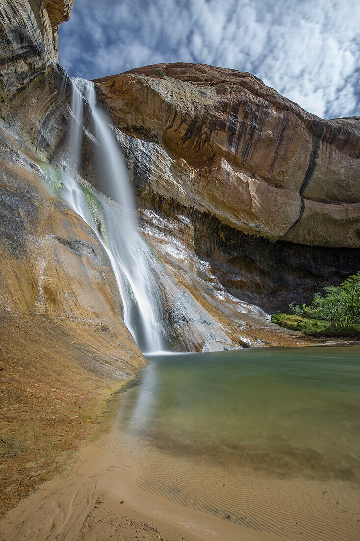Waterfall and small lake against a blue sky. Lower Calf Creek Falls