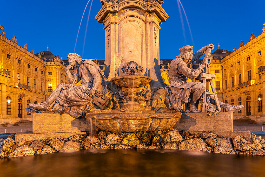 Frankoniabrunnen mit Walther von der Vogelweide und Tilman Riemenschneider vor der Würzburger Residenz in der Abenddämmerung, Würzburg, Bayern, Deutschland  