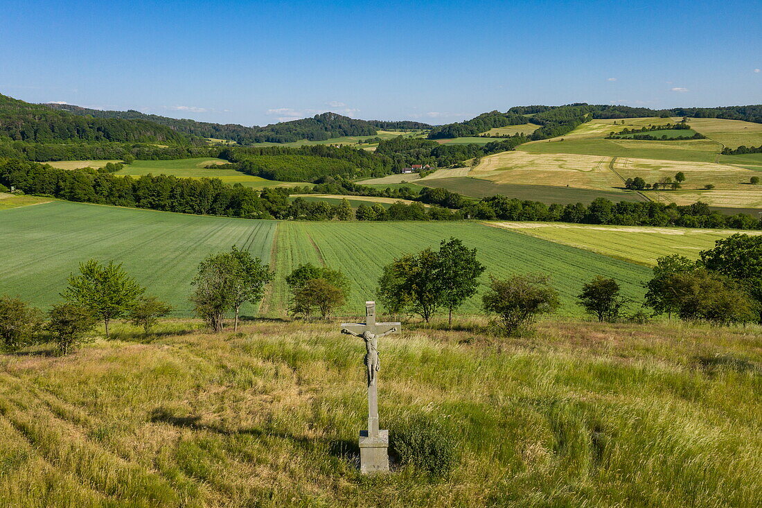 Crucifix on a slope in fields in the Hessisches Kegelspiel region, Nüsttal Oberaschenbach, Rhön, Hesse, Germany