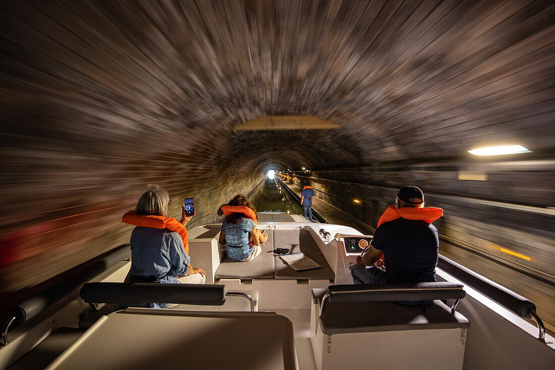 Besatzung mit Schwimmwesten an Bord von einem Le Boat Horizon 5 Hausboot bei Fahrt durch Tunnel auf dem Canal de la Marne au Rhin, Saint-Louis,  Moselle, Grand Est, Frankreich