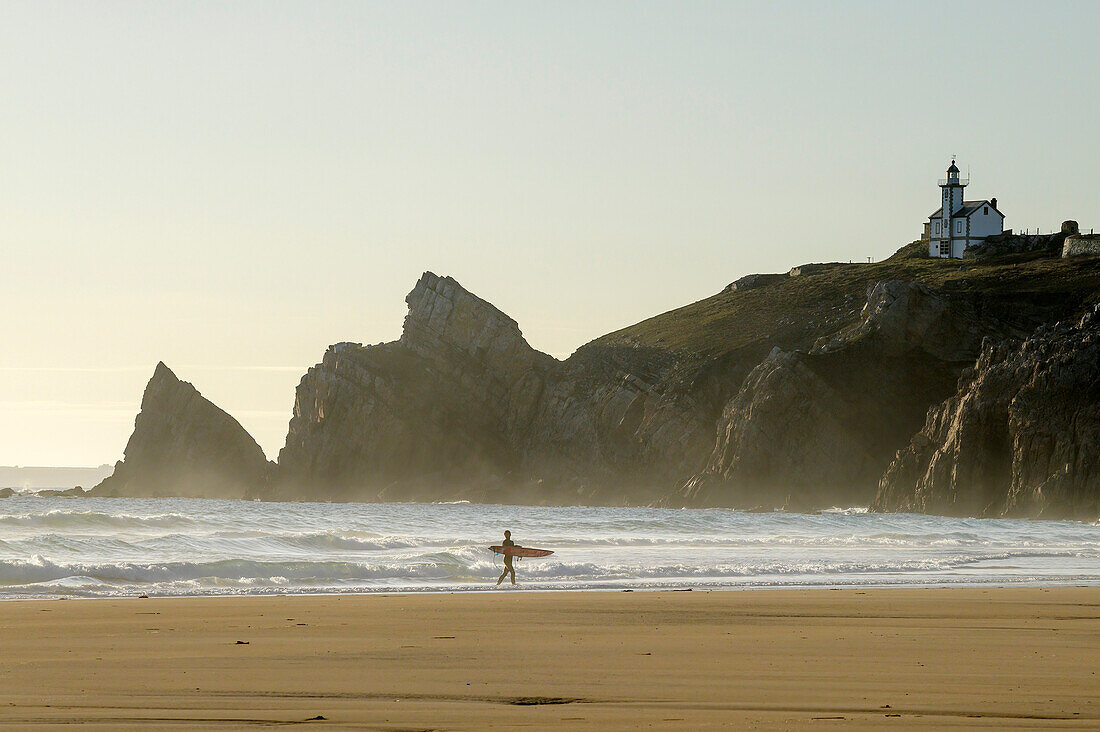Surfer walks across the Plage de Pen Hat beach, Pointe du Toulinguet in the background, Camaret-sur-Mer, GR 34, Zöllnerweg, Sentier Côtier, Crozon peninsula, Atlantic coast, Brittany, France