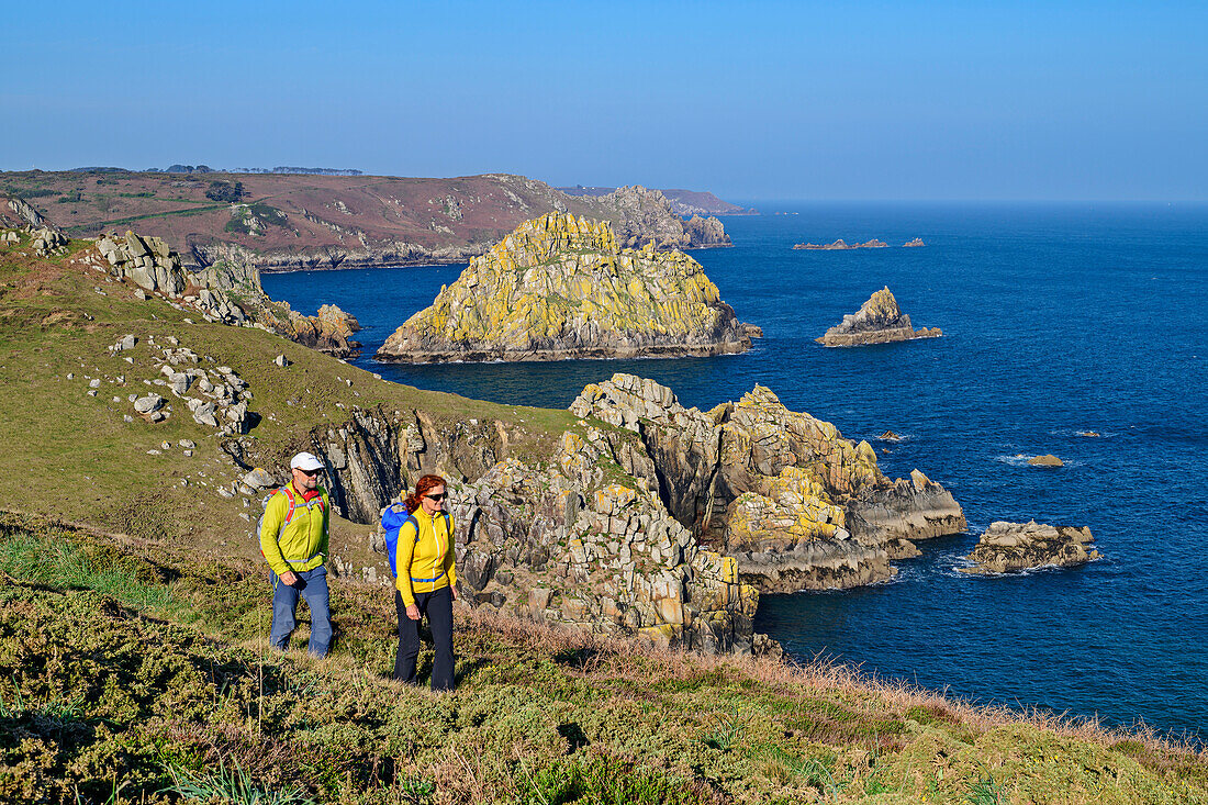 Man and woman hiking on the Zöllnerweg at Cap Sizun with the sea and rocky islands in the background, Cap-Sizun, GR 34, Zöllnerweg, Brittany, France