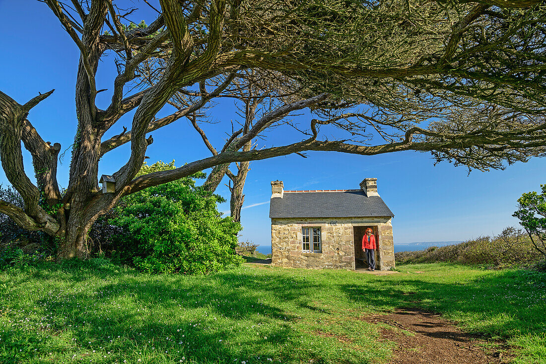 Frau beim Wandern steht vor Hütte Ti Felix, Cap-Sizun, GR 34, Zöllnerweg, Bretagne, Frankreich