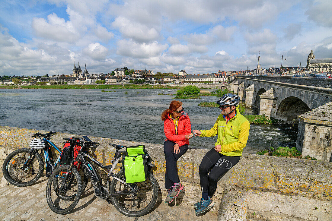 Man and woman cycling on the Loire cycle path taking a break, Loire and Blois in the background, Blois, Loire Castles, Loire Valley, UNESCO World Heritage Loire Valley, France