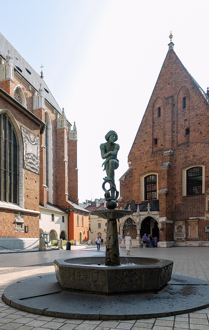 Plac Mariacki mit Pomnik-Zaka-Brunnen mit Skulptur des Studenten Zaka und Marienkirche (Kościół Mariacki) in der Altstadt von Kraków in Polen