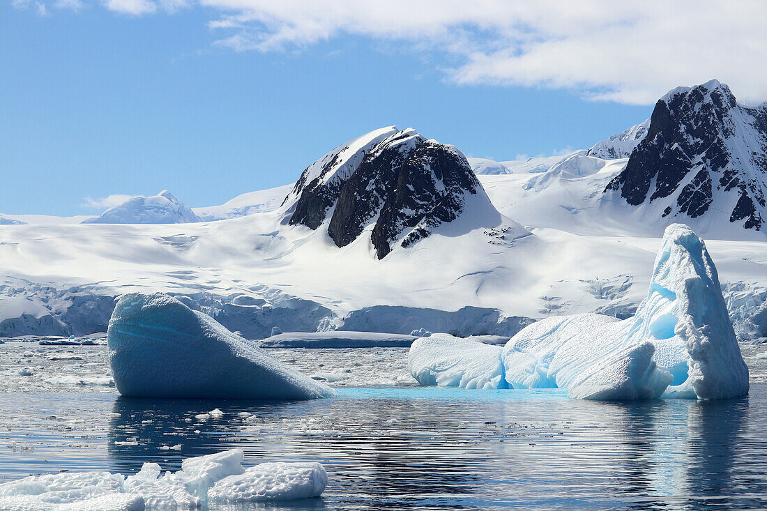 Antarktis; antarktische Halbinsel; bei Yalour Island; Schnee bedeckte Gebirge; im Vordergrund türkis leuchtender Eisberg