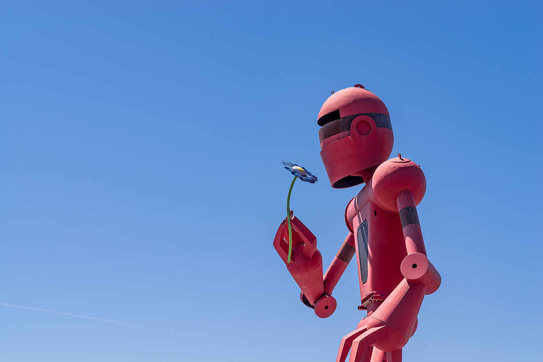 A giant statue of a robot holding a metal flower at the entrance of Meow Wolf in Santa Fe, New Mexico.