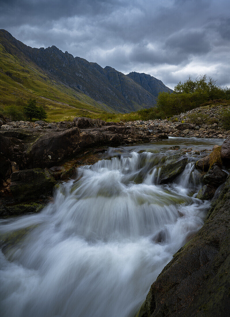 Wasserfall zwischen den Bergen, Glencoe, Schottland, Vereinigtes Königreich