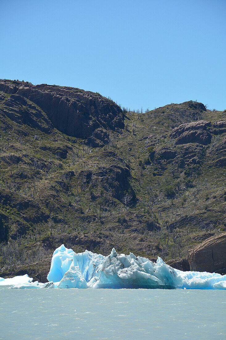 Chile; Südchile; Region Magallanes; Gebirge der südlichen Cordillera Patagonica; Nationalpark Torres del Paine; Lago Grey; im Vordergrund Eisberg; im Hintergrund felsige Hügellandschaft