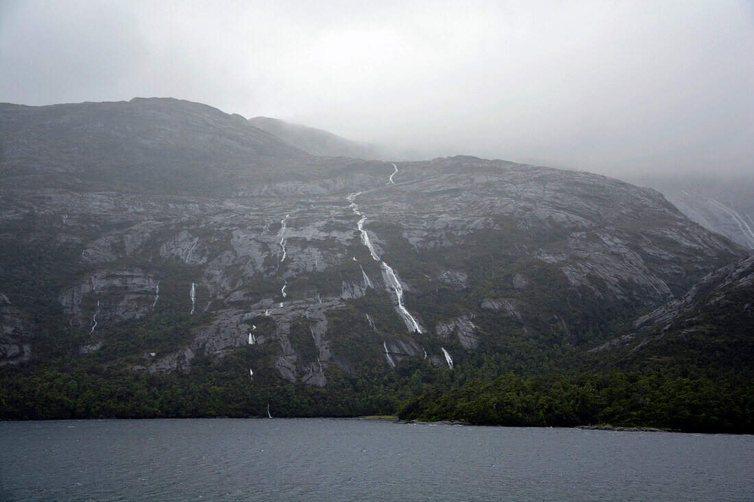 Chile; Südchile; Region Magallanes; Gebirge der südlichen Cordillera Patagonica; auf der Navimag Fähre durch die patagonischen Fjorde; Kanal Concepcion; tief hängende Regenwolken; Regen