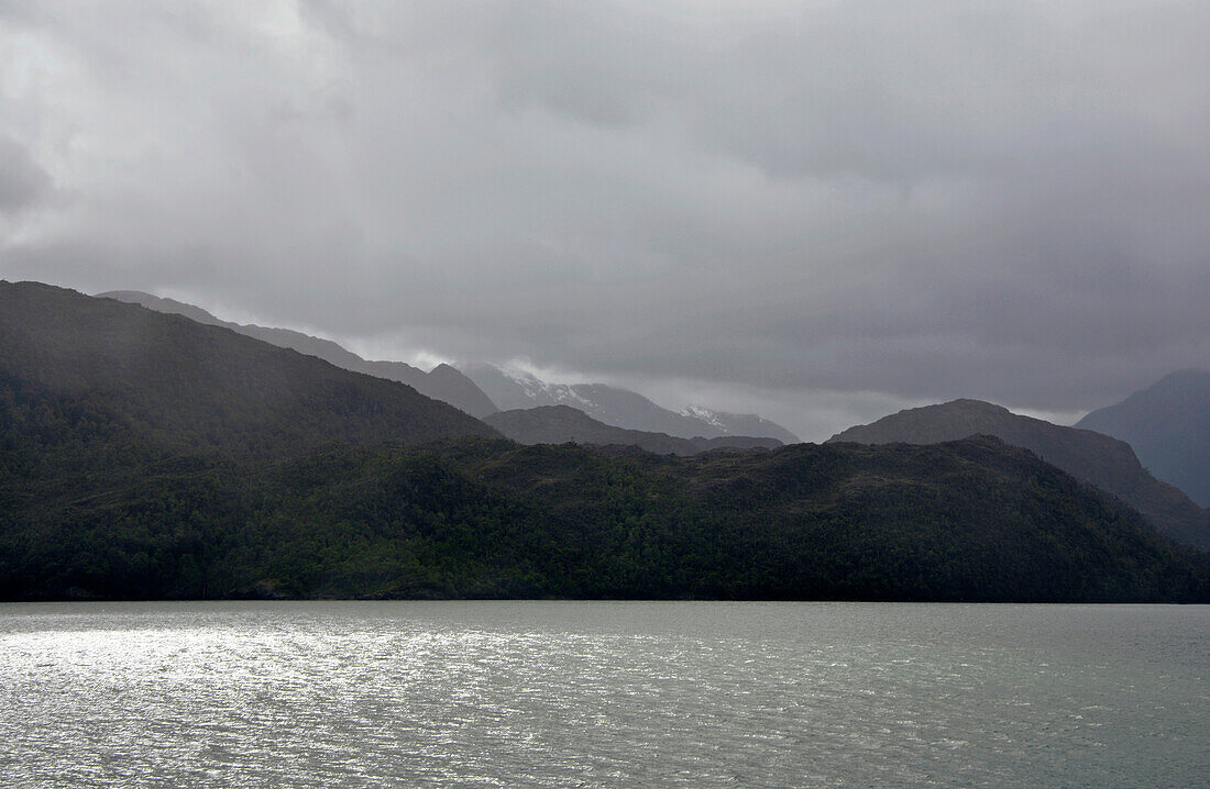 Chile; Southern Chile; Magallanes Region; Mountains of the southern Cordillera Patagonica; on the Navimag ferry through the Patagonian fjords; Angostura Inglesa or English Narrows; low hanging rain clouds; Rain and sun alternate