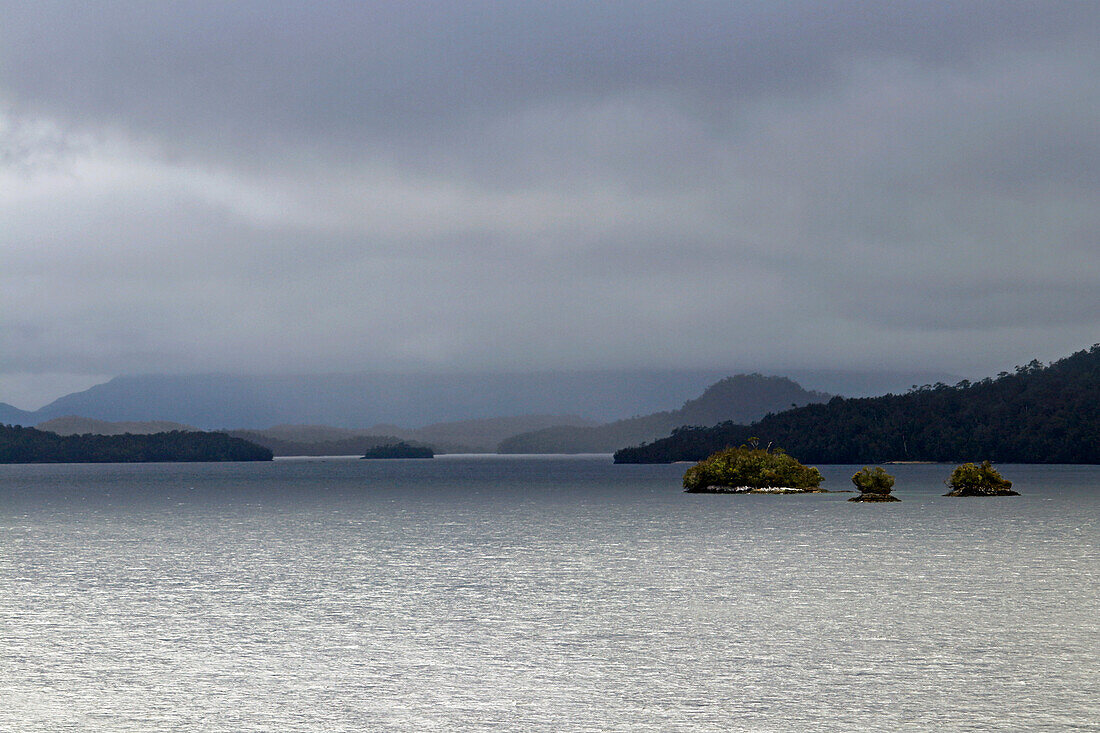 Chile; Southern Chile; Aysen region; Mountains of the southern Cordillera Patagonica; on the Navimag ferry through the Patagonian fjords; Islands in the Polluche Canal; low hanging rain clouds and sun alternate