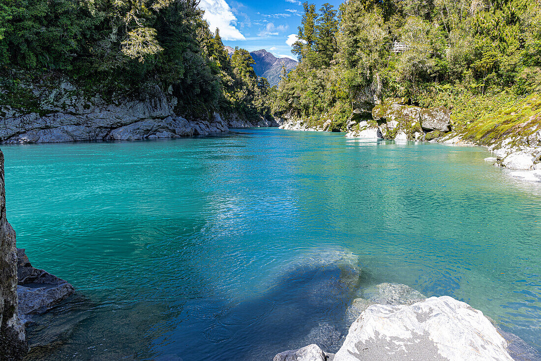 Turquoise waters flow through the Hokitika Gorge amidst lush vegetation and rock formations.