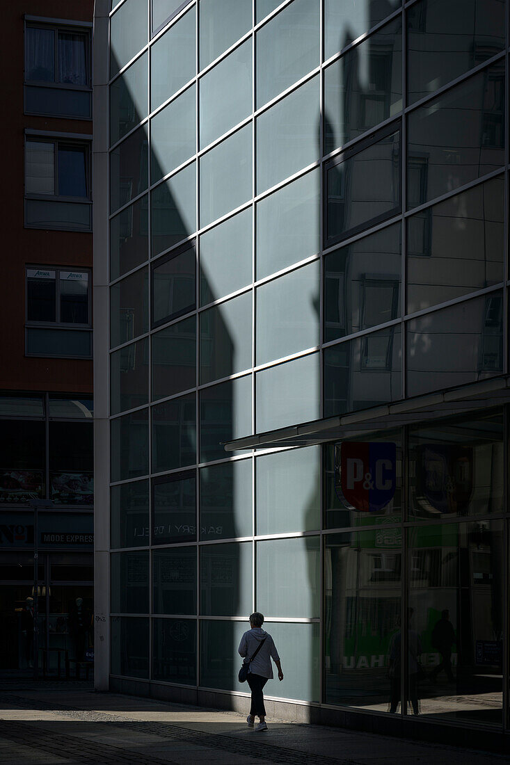 Woman walking along modern facade of a department store, Chemnitz, Saxony, Germany, Europe