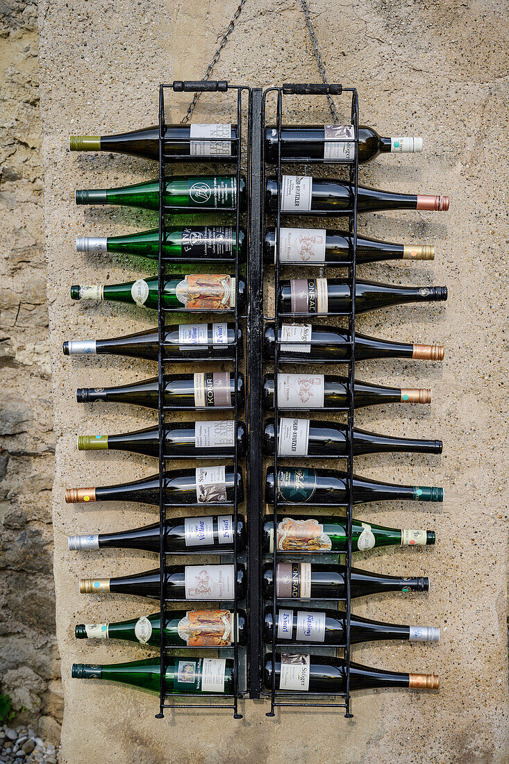 An einer Hauswand sind leere Weinflaschen von Winzern der Region präsentiert, UNESCO Welterbe "Kulturlandschaft Wachau", Dürnstein, Niederösterreich, Österreich, Europa