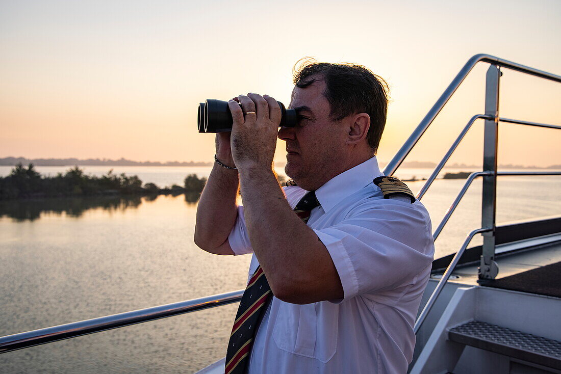 Kapitän blickt durch ein Fernglas von an Bord Flusskreuzfahrtschiff nickoVISION (nicko cruises) auf der Donau, in der Nähe von Bratislava, Bratislava, Slowakei, Europa