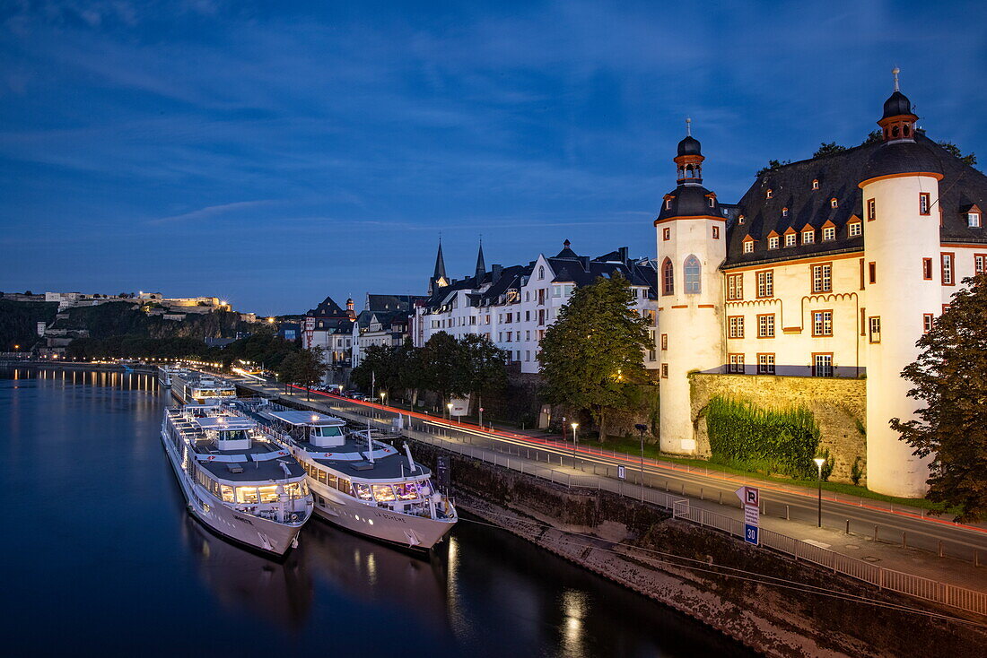 Flusskreuzfahrtschiffe liegen an der Mosel mit der Festung Ehrenbreitstein in der Ferne in der Abenddämmerung, Koblenz, Rheinland-Pfalz, Deutschland, Europa
