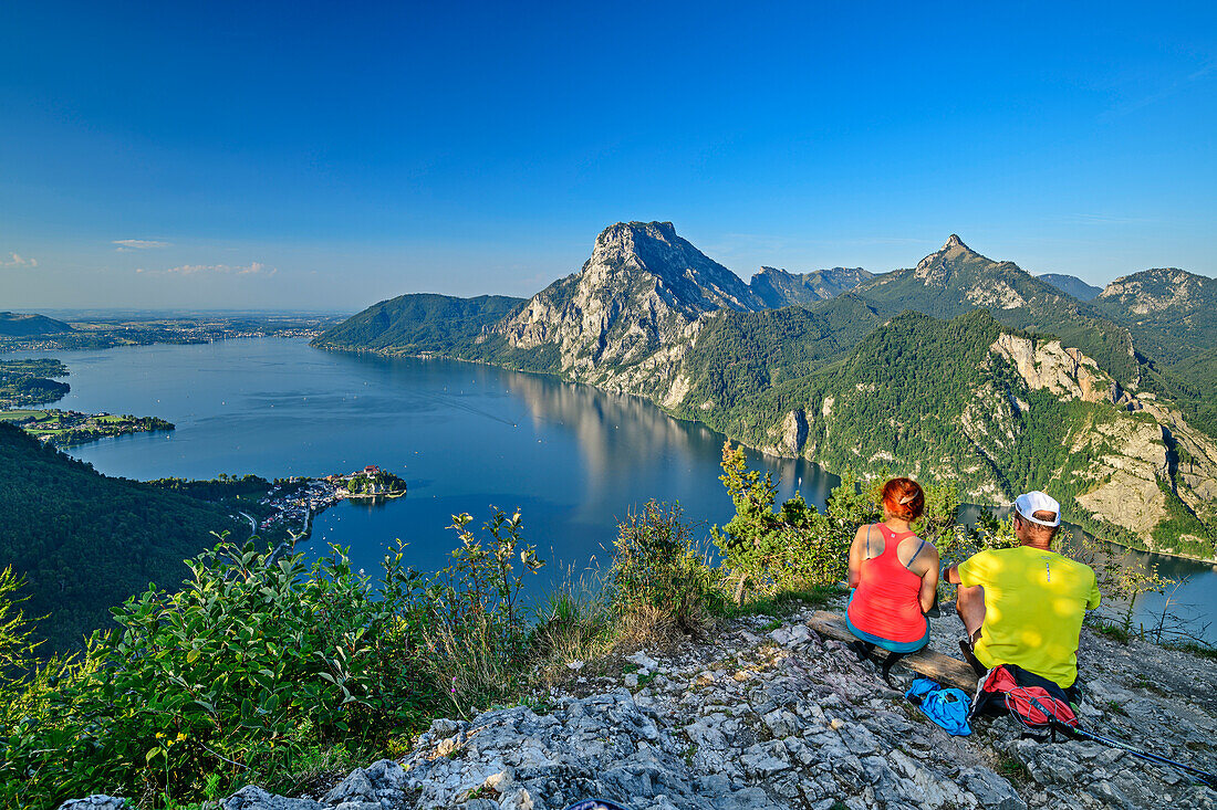 Man and woman hiking sitting on Kleiner Sonnstein and looking at Traunsee and Traunstein, from Kleiner Sonnstein, Salzkammergut Mountains, Salzkammergut, Upper Austria, Austria