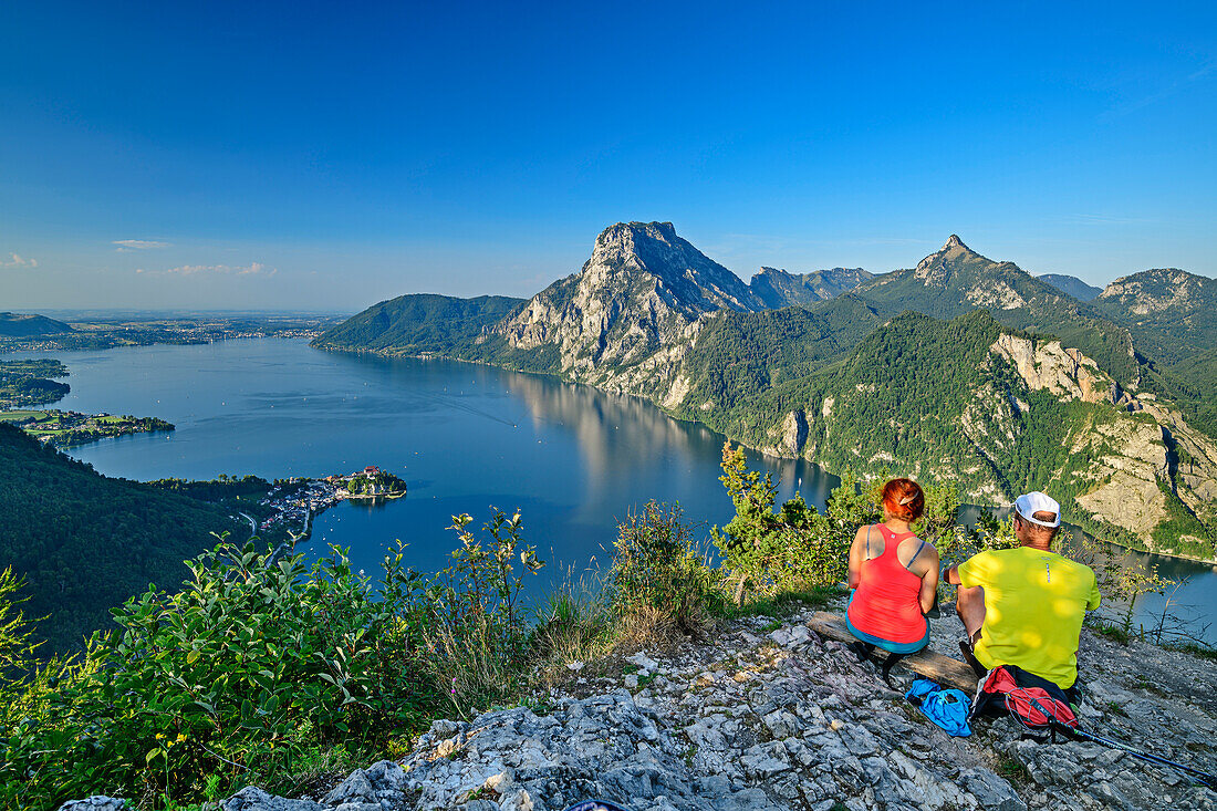 Mann und Frau beim Wandern sitzen am Kleinen Sonnstein und blicken auf Traunsee und Traunstein, vom Kleinen Sonnstein, Salzkammergutberge, Salzkammergut, Oberösterreich, Österreich