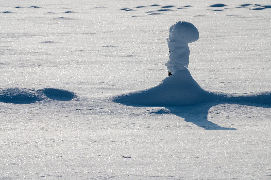 Verschneiter Zaun im Winter, Pfosten wirft Schatten auf Schnee