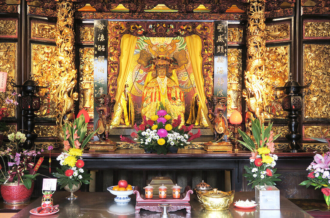  A magnificent golden altar with floral decorations and offerings in the Empress Zhusheng Hall at Dalongdong Baoan Temple, Taipei, Taiwan 