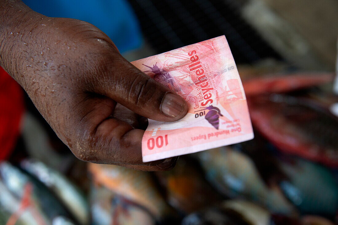 Hand hält eine 100-Seychellen-Rupie-Banknote, Victoria, Mahé Island, Seychellen, Indischer Ozean