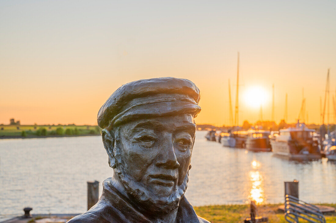 Statue 'Der Netzflicker' im Fischereihafen von Greetsiel bei Sonnenaufgang, Krummhörn, Ostfriesland, Niedersachsen, Deutschland