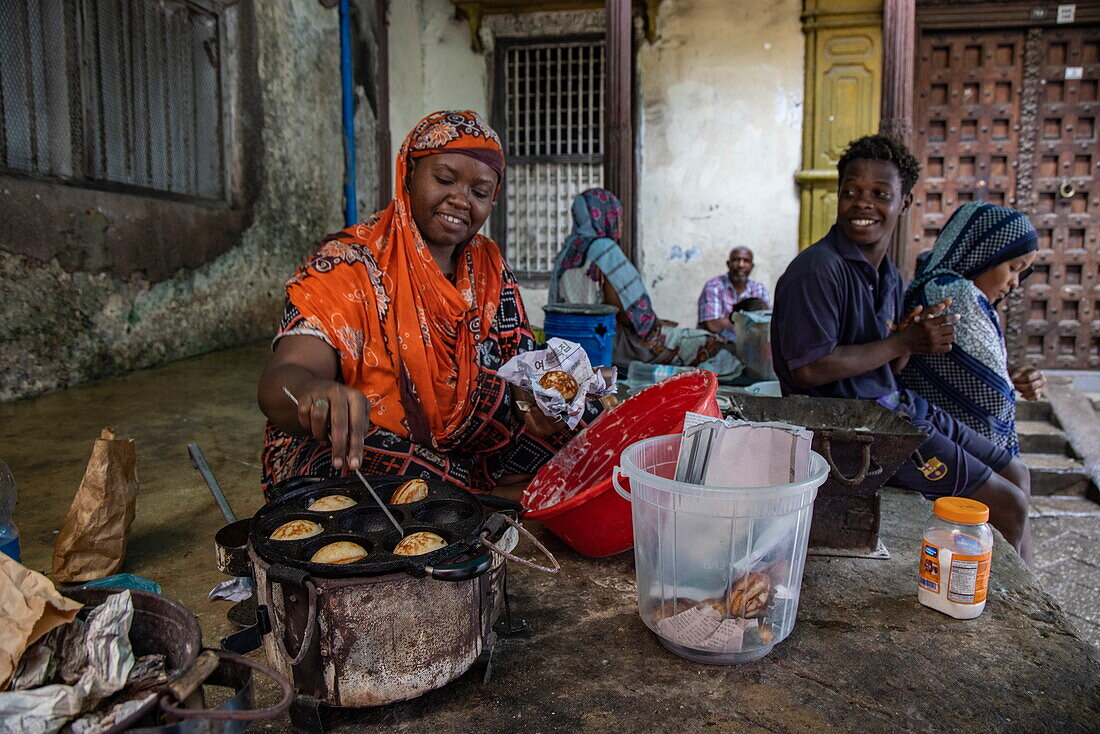 Frau bereitet Teigtaschen in einer gusseisernen Pfanne über Kohlen zu, Stonetown, Sansibar-Stadt, Sansibar, Tansania, Afrika