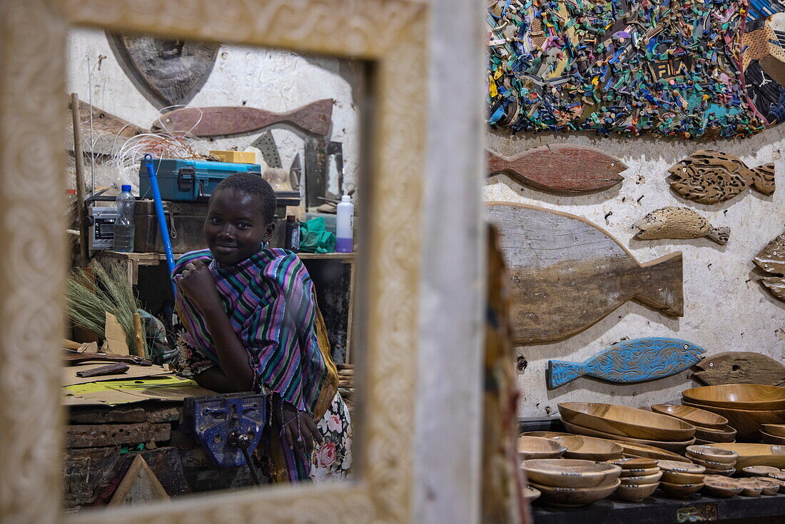 Spiegelung einer jungen Frau im Kunsthandwerksladen, Lamu, Insel Lamu, Kenia, Afrika