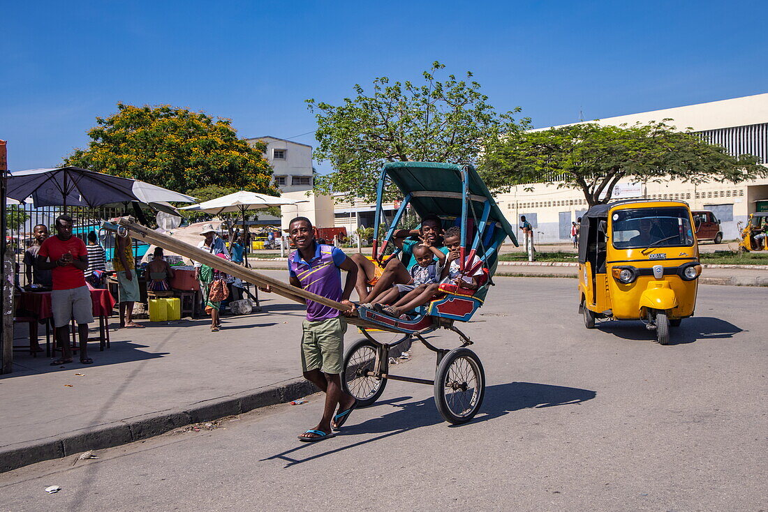 Straßenszene, Einheimischer zieht eine Rikscha und typisches Tuk-Tuk, Mahajanga, Boeny, Madagaskar, Indischer Ozean