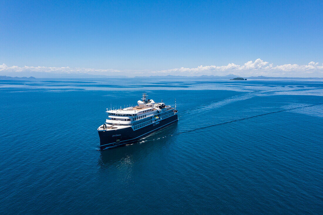  Aerial view of expedition cruise ship SH Diana (Swan Hellenic) with islands in the distance, near Nosy Be, Diana, Madagascar, Indian Ocean 
