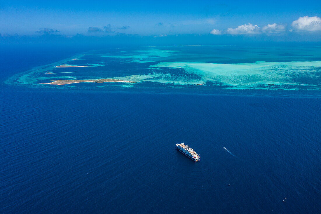 Luftaufnahme des Expeditionskreuzfahrtschiffes SH Diana (Swan Hellenic) und Riff vor der Insel Cosmoledo Atoll, Äußere Seychellen, Seychellen, Indischer Ozean