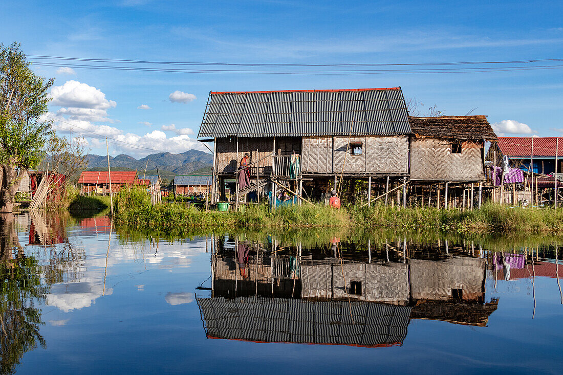 Ein traditionelles Stelzenhaus am Inle-See im urmesischen Myanmar im Shan-Staat, Südostasien, spiegelt sich malerisch bei Sonnenschein