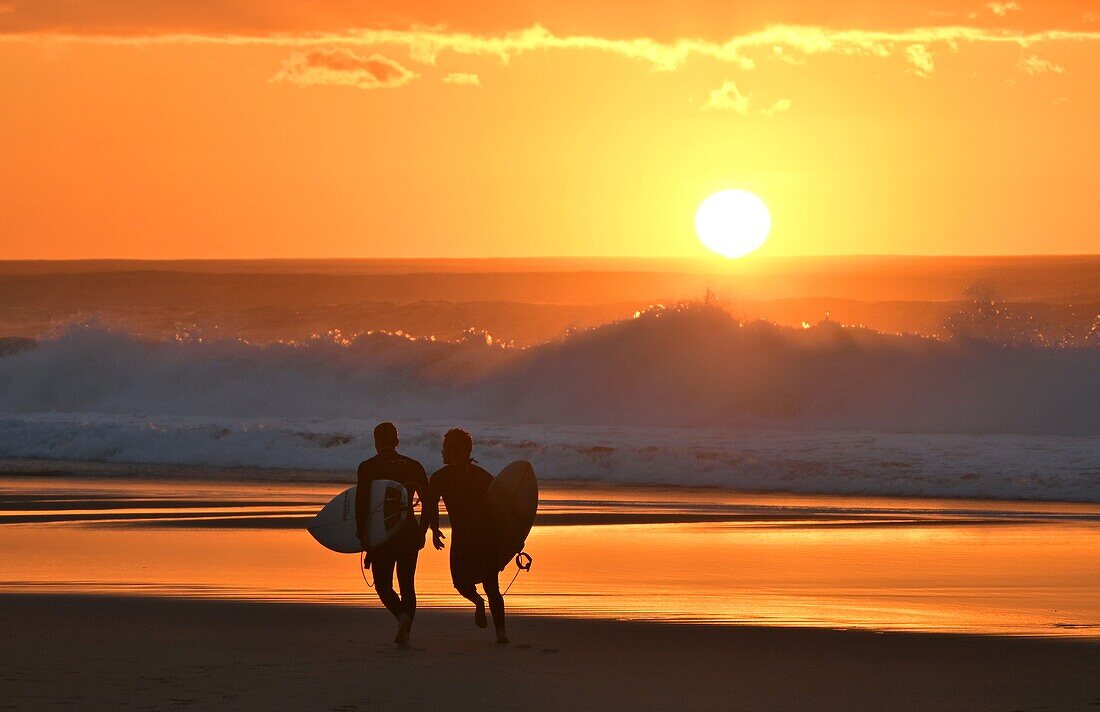 Surfer vor hohen Wellen, am Strand Praia do Guincho bei Sonnenuntergang, Atlantik, bei Cascais, Region Lissabon, Portugal