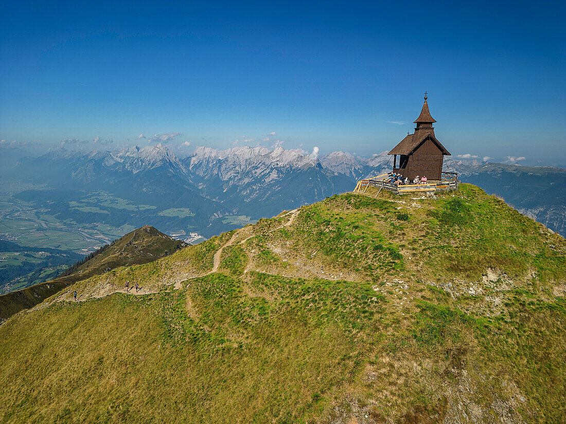  Several people sit at the chapel at the summit of the Kellerjoch, Inntal and Karwendel in the background, Kellerjoch, Tux Alps, Tyrol, Austria 