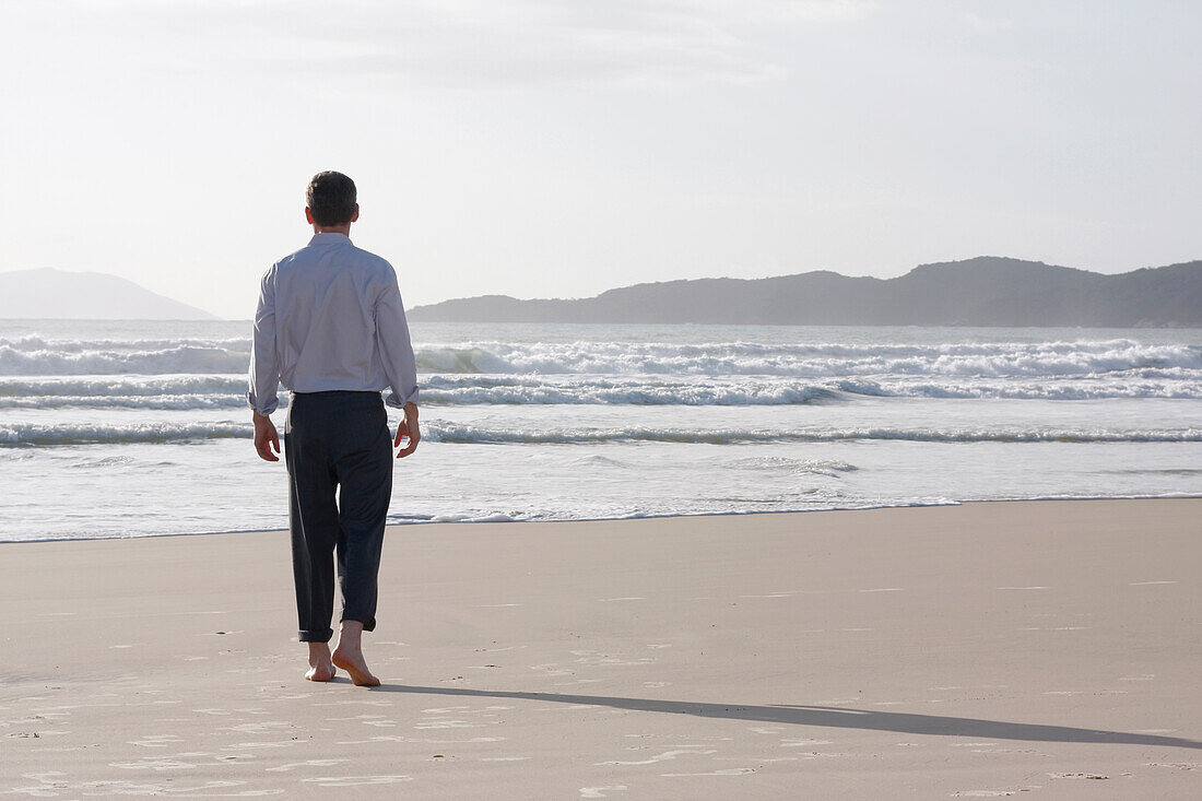  Businessman walks barefoot on the beach, Bombinhas, Santa Catarina, Brazil 