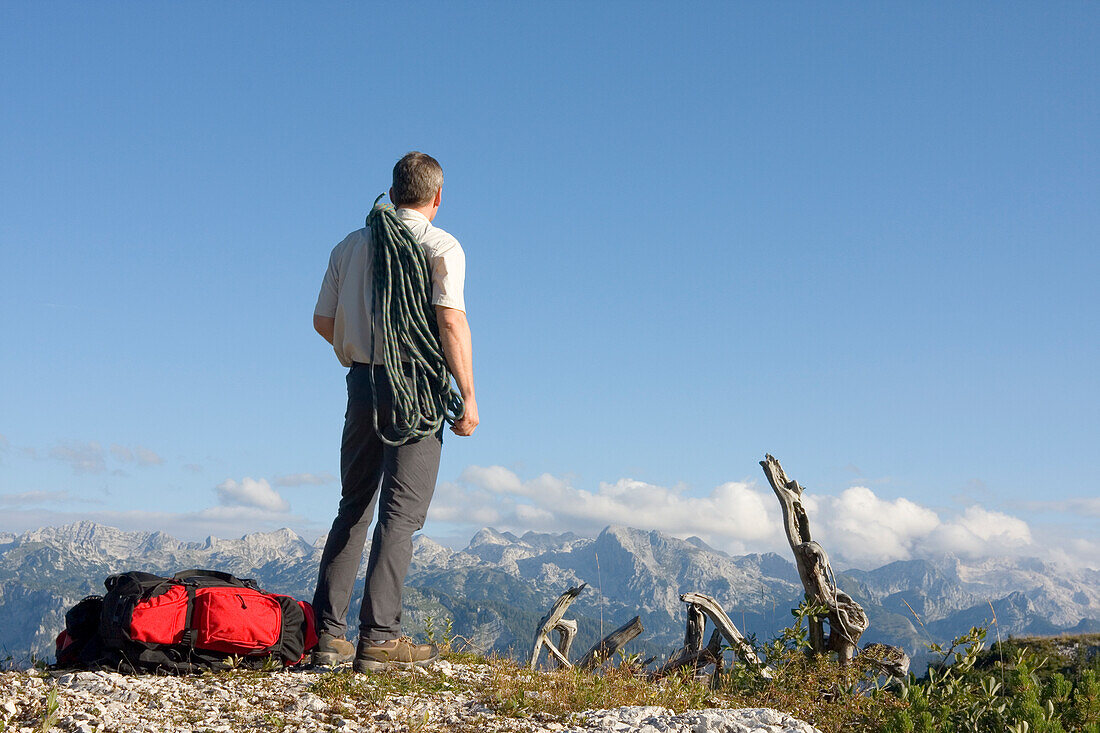 Bergsteiger steht auf einem Gipfel im Triglav Nationalpark, Ukanc, Slowenien