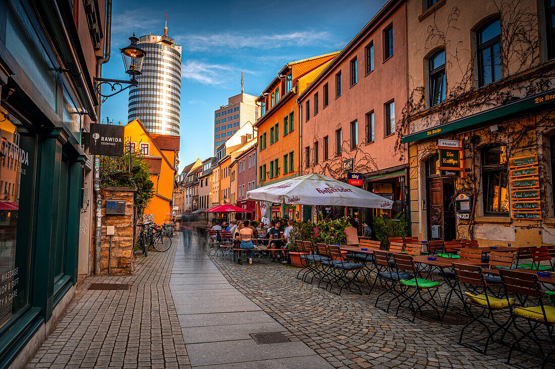  The restaurant street Wagnergasse with the Jentower in the background at sunset and blue sky, Jena, Thuringia, Germany 