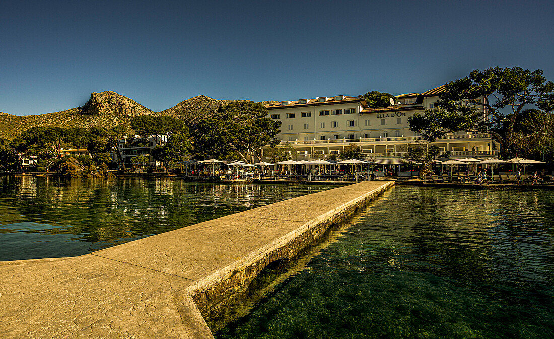 Blick vom Bootssteg auf das Hotel Illa d'Or am Pine Walk, im Hintergrund das Tramuntana-Gebirge, Port de Pollenca, Mallorca, Spanien