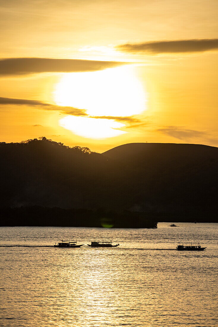  Silhouette of Bangka outrigger canoe tour boats and coast at sunset, Coron, Palawan, Philippines 