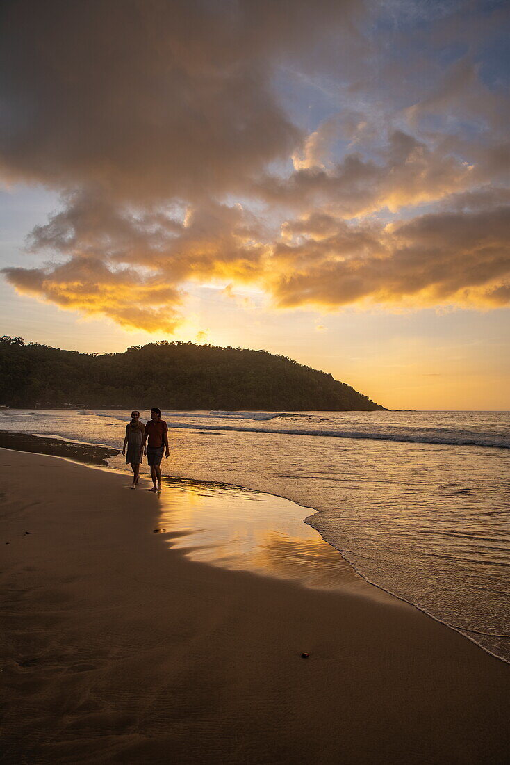  Silhouette of a couple walking along Nagtabon Beach at sunset, Bacungan, near Puerto Princesa, Palawan, Philippines 